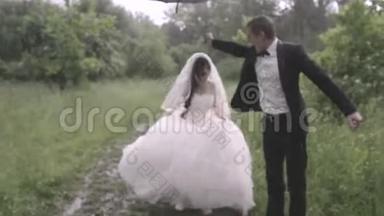 喜洋洋的新婚夫妇在雨中撑着伞